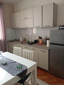 a kitchen with white cabinets and a table and a refrigerator at Apartman Radanović in Foča