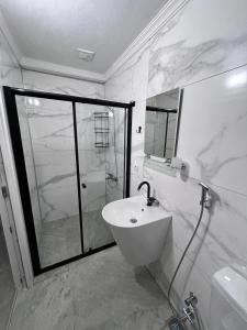 ein weißes Bad mit einer Dusche und einem Waschbecken in der Unterkunft YALI Apart Hotel in Trabzon