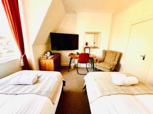a room with two beds and a desk and a tv at Doune Guest House in St Andrews