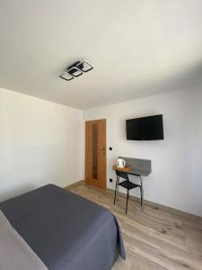 梅爾諾的住宿－DAWIDEK，一间卧室配有一张床、一张书桌和一台电视。