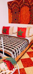 um quarto com uma cama com almofadas vermelhas e verdes em SULTANA Beach Riad em Saïdia