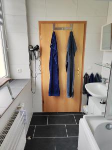 ein Badezimmer mit einer Tür mit blauen Bademänteln darauf in der Unterkunft Ferienwohnungen An der Fichtelbergbahn in Cranzahl