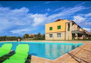 ein Haus mit einem Pool und zwei Gartenstühlen in der Unterkunft Jovì`s Apartment in Tar
