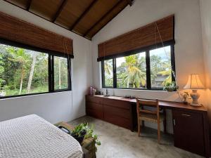 a bedroom with a bed and a desk and two windows at Rai Villa Colombo in Colombo