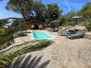 a pool with chairs and umbrellas next to a house at Carpediem corsica adult only in Poggio-dʼOletta