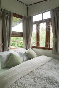 a bed with white sheets and pillows in front of a window at Suksamer Relaxation Homestay 