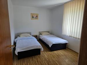 two beds in a small room with a window at Apartman Rakovica in Sarajevo