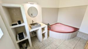 a bathroom with a pink tub and a sink at Maison conviviale lac & jardin in Mesnil-Saint-Père