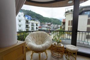 Tropical Paradise Sapa Hotel & Coffee في سابا: بلكونه فيها كرسي ابيض ونافذه كبيره
