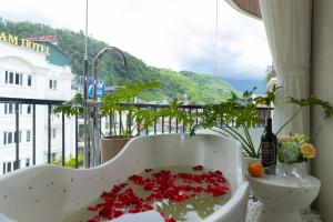 Tropical Paradise Sapa Hotel & Coffee في سابا: حوض استحمام مليء بالورود على الشرفة