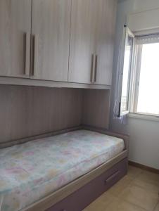 a bed in a room with a window and white cabinets at LA FINESTRA SUL MARE in Lendinuso