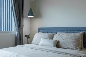 een bed met witte lakens en een blauw hoofdeinde en een raam bij DeCozy - KUCHING CITY - 2Studios 7Pax in Kuching