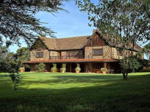 a large wooden house with a green lawn at Mukima Manor in Nanyuki