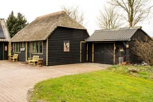 a black building with a thatched roof and a yard at Gastenverblijf De Weldadigheid in Eesveen
