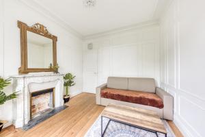 ein Wohnzimmer mit einer Couch und einem Spiegel in der Unterkunft Coup de cœur parisien à 15 mn de Paris - 45 mn Disney in Noisy-le-Sec + 4 Fotos