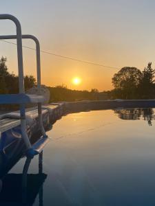 una piscina con la puesta de sol en el fondo en Casa Alfazema do Monte, en Santa Marta