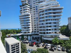 a large white building with cars parked in a parking lot at SeaView Lazur Apartment in Burgas City