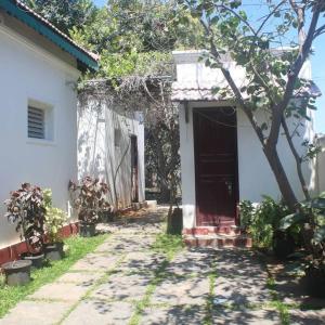 a white house with a red door and a tree at Hertiage Blue Vila in Mahabalipuram