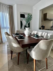 una mesa de comedor con sillas blancas y un comedor en GreenHome 75 inch TV 5mints from the beach and City, en Dar es Salaam