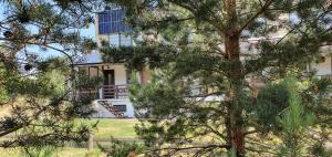 una casa detrás de unos árboles frente a un edificio en Apartamentas Kurėnas, en Nida