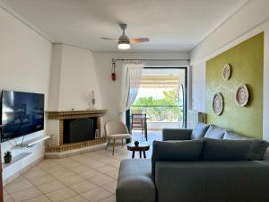 a living room with a couch and a television at Saronida365 Sea & Sunset view in Saronida