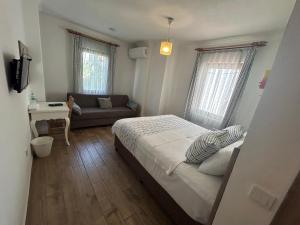 ein kleines Schlafzimmer mit einem Bett und einer Couch in der Unterkunft Bozcaada Vitis Hotel in Bozcaada