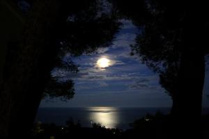 a full moon over the ocean at night at Hostal Sa Barraca - Adults Only in Begur