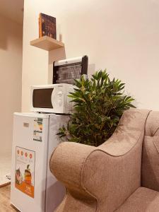 - un four micro-ondes installé au-dessus d'un réfrigérateur à côté d'un canapé dans l'établissement بيتي بلس للغرف الفندقية- مدخل مستقل, à Riyadh Al Khabra