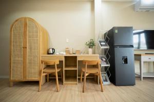 eine Küche mit einem Tisch, einem Kühlschrank und Stühlen in der Unterkunft Secret Elm Hotel in Ho-Chi-Minh-Stadt