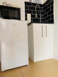 a kitchen with a white refrigerator and a microwave at Ouklip Place Hotels in Roodepoort