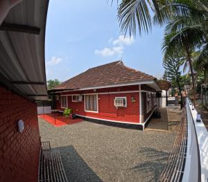 ein rotes Haus auf einer Straße mit einer Palme in der Unterkunft vintage valley urban cottage in Thodupuzha