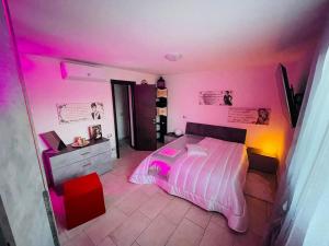 にあるAppartamento a Udine con doccia idromassaggioのピンクの照明とベッドが備わるベッドルーム1室