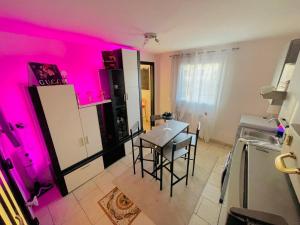 eine Küche mit rosafarbener Beleuchtung und einem Tisch mit Stühlen in der Unterkunft Appartamento a Udine con doccia idromassaggio 