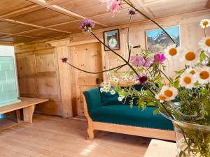 un sofá azul en una habitación con un jarrón de flores en Bregenzerwälderhaus Ambros, en Bezau