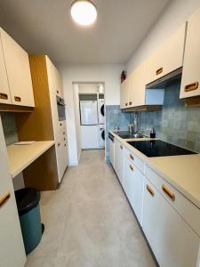 a kitchen with white cabinets and a sink at Large sunny and bright apartment with park view in Ostend