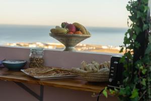una mesa con un tazón de fruta y un tazón de pan en Monkey's Guest House - Appartement roof top terrasse privée vue sur mer, en Tamraght Ouzdar