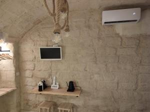 a stone wall with a desk with a phone and a tv at La Cas d Zii la Giulia in Bari