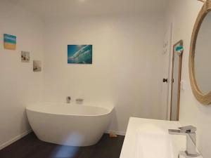 a white bath tub in a bathroom with a mirror at Bay and Karioi view in town in Raglan +21 photos