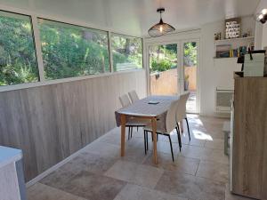 una sala da pranzo con tavolo, sedie e finestre di Villa Cutalello coté montagne Calenzana a Calenzana