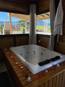 a bath tub in a room with a large window at Chalés Refúgio Ohana in Urubici