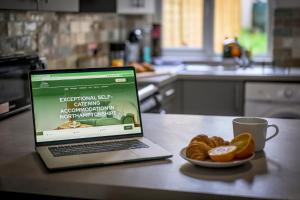 a laptop computer sitting on a counter with a plate of food at Vale House By EDEN Accommodation - 2 Bedroom Whole House, Sleeps 4 - NEWLY RENOVATED in Kettering +35 photos