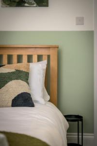 a bed with a wooden headboard and white pillows at Vale House By EDEN Accommodation - 2 Bedroom Whole House, Sleeps 4 - NEWLY RENOVATED in Kettering