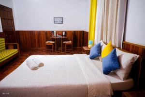 a bedroom with a large bed with blue and yellow pillows at L'anis Etoilé in Antsirabe