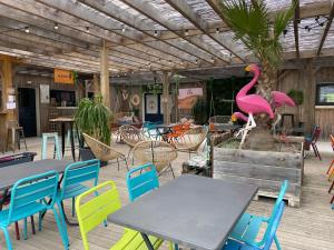 eine Terrasse mit Tischen und Stühlen und einer rosa Flamingo-Statue in der Unterkunft Mobil-home Confort TV CLIM Narbonne-Plage in Narbonne-Plage