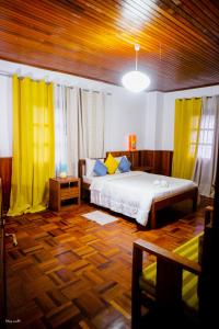 a bedroom with a bed and yellow drapes at L'anis Etoilé in Antsirabe