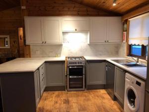 a kitchen with white cabinets and a stove top oven at Cozy Cabin with Stunning Loch Lomond Views in Rowardennan