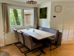 a dining room with a wooden table and chairs at Kindvriendelijk sfeervol vakantiehuis Bosgeneugte bij zwembad op de Veluwe in Doornspijk +37 photos