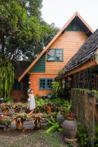 a girl walking in front of a house with plants at Ban MaeBo Local Stay in Ban Nong Han