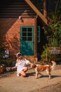 a woman in a white dress petting a dog at Ban MaeBo Local Stay in Ban Nong Han