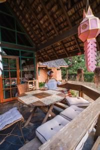 a person sitting at a table on a patio at Ban MaeBo Local Stay in Ban Nong Han